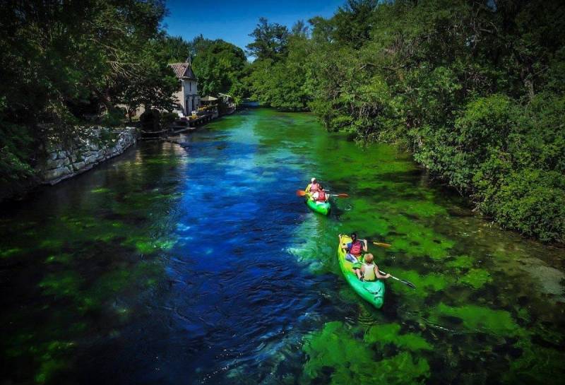 Canoe kayak naviguant sur l'eau bleu de la Sorgue dans le Vaucluse
