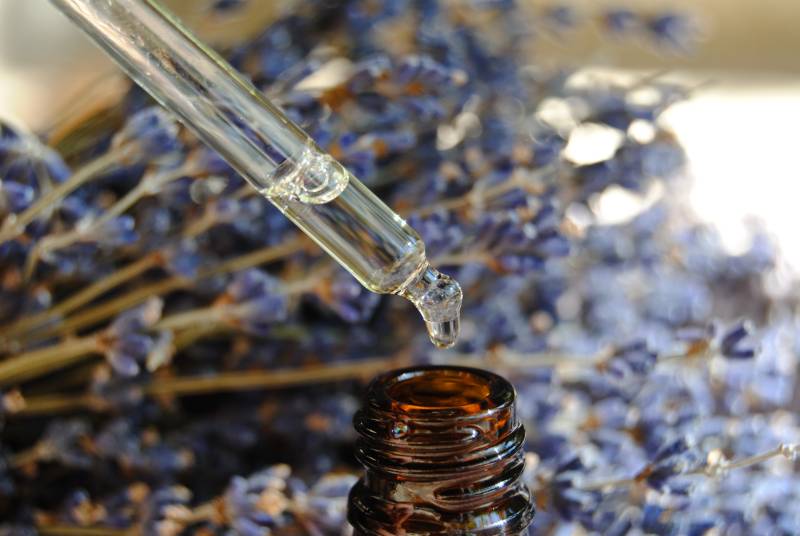 Pipette d'huile essentielle de lavande fine avec bouquet de lavande en arrière plan